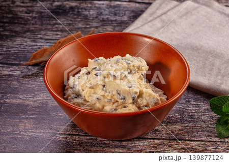 Creamy cottage cheese with raisins in brown bowl on rustic wooden table Creamy cottage cheese with raisins in brown bowl on rustic wooden table 139877124
