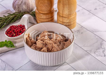 Savory liver pate in ceramic bowl with rosemary, basil, and pink peppercorns on kitchen table Savory liver pate in ceramic bowl with rosemary, basil, and pink peppercorns on kitchen table 139877133