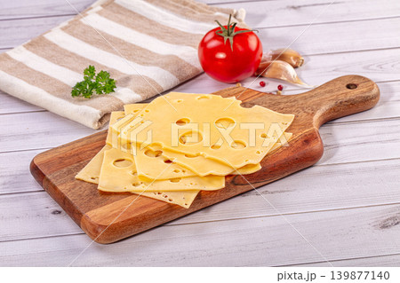 Sliced Swiss cheese on wooden cutting board with fresh tomato and garlic 139877140