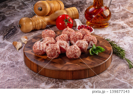 Raw meatballs with fresh herbs and spices on wooden cutting board Raw meatballs with fresh herbs and spices on wooden cutting board 139877143