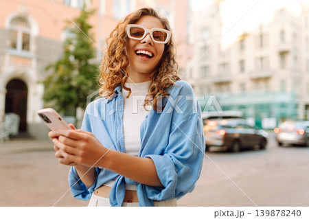 Portrait happy woman walking with phone in city. Online Communication with friend. Lifestyle concept Portrait happy woman walking with phone in city. Online Communication with friend. Lifestyle concept 139878240