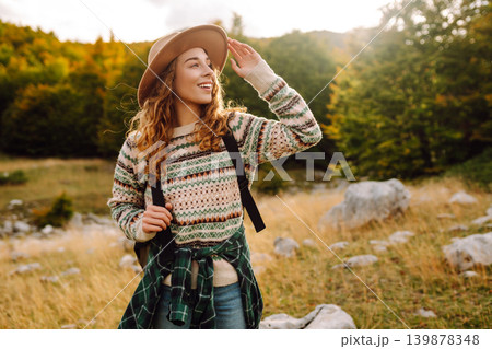 Young woman enjoys sunny afternoon in mountains while sitting on rocks. Tourism. Active lifestyle. Young woman enjoys sunny afternoon in mountains while sitting on rocks. Tourism. Active lifestyle. 139878348