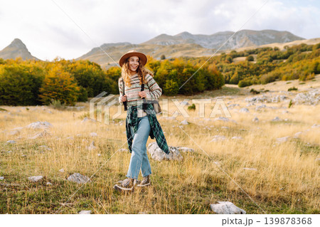 Young woman enjoys sunny afternoon in mountains while sitting on rocks. Tourism. Active lifestyle. Young woman enjoys sunny afternoon in mountains while sitting on rocks. Tourism. Active lifestyle. 139878368