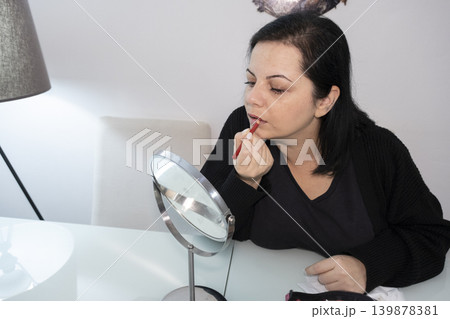 Woman Applying Makeup in Front of Mirror. 139878381