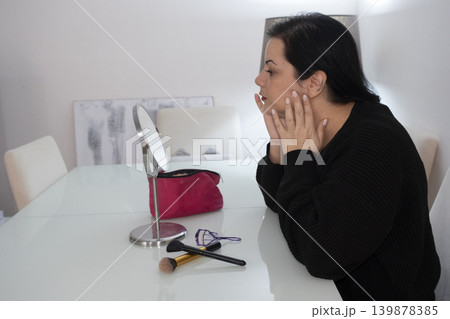 Woman Applying Makeup in Front of Mirror. 139878385