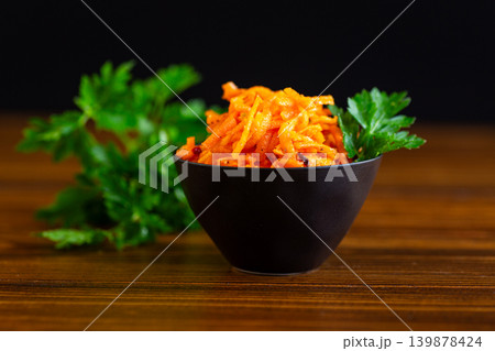 Korean carrot salad in black bowl on dark wooden background Korean carrot salad in black bowl on dark wooden background 139878424