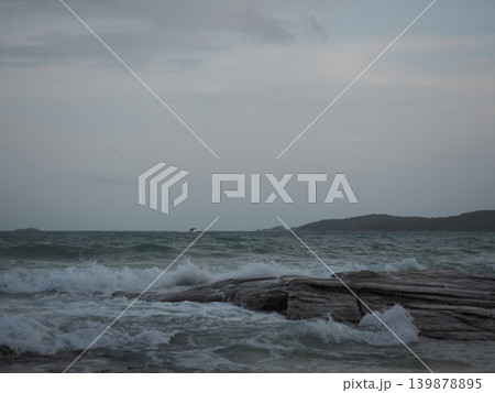 Ocean wave rock shore sea cloudy sky coastline horizon surf breaks on dark stone under overcast evening light calm mood Ocean wave rock shore sea cloudy sky coastline horizon surf breaks on dark stone under overcast evening light calm mood 139878895