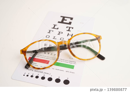 Glasses on eye testing exam chart to check eyesight accuracy of reading. Glasses on eye testing exam chart to check eyesight accuracy of reading. 139880877