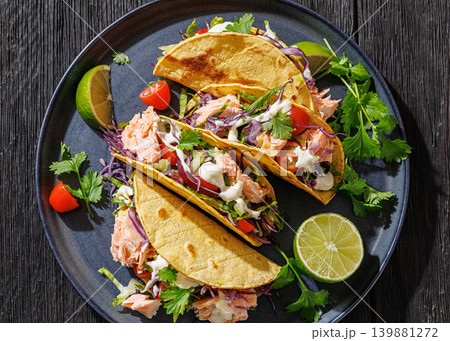 salmon tacos drizzled with sauce on a plate 139881272
