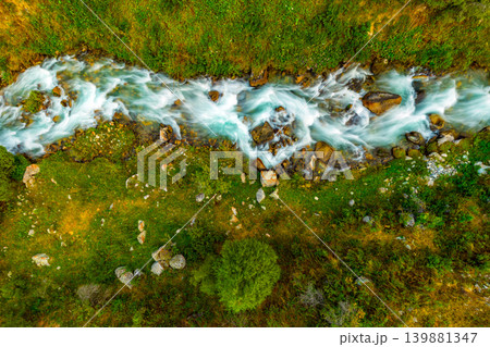Aerial View of a Mountain Stream Flowing Through Grassy Terrain of Kyrgyzstan 139881347