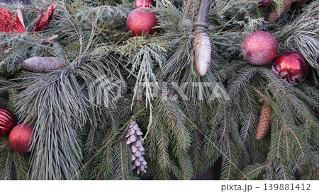 Close-up of a Christmas composition made of natural pine and spruce branches, cones, and red Christmas tree balls. Close-up of a Christmas composition made of natural pine and spruce branches, cones, and red Christmas tree balls. 139881412