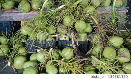 Large pile of fresh green coconuts displayed on a market counter at an Asian outdoor market stall. Tropical produce concept Large pile of fresh green coconuts displayed on a market counter at an Asian outdoor market stall. Tropical produce concept 139881520