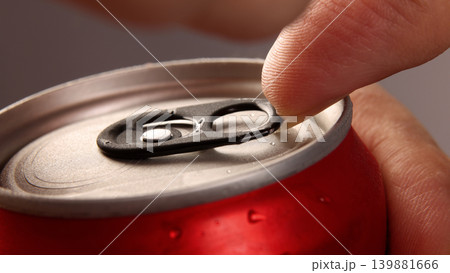 Cola or soda can opening. Close up of hand open aluminum beverage can with pull tab. Refreshing Cola or soda carbonated soft drink container with metal texture condensation droplets and easy open lid 139881666