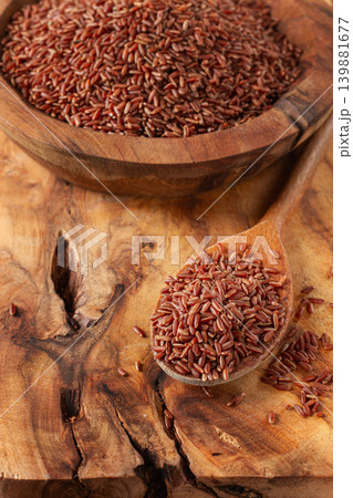 Natural red rice, in a wooden bowl and spoon on a wooden surface in rustic style, top view 139881677