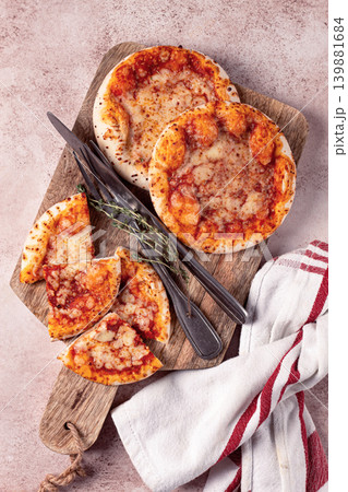 Four pizzetta Margaritas, on a cutting board, on a light gray surface, top view, 139881684