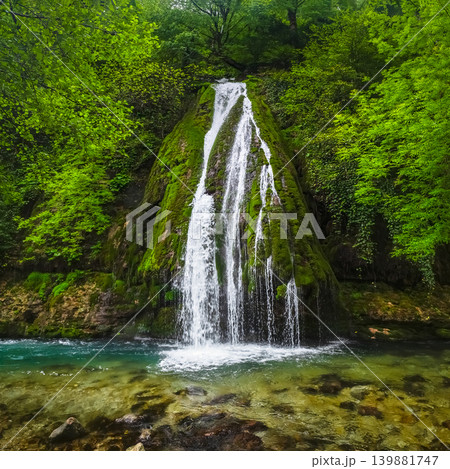 Vibrant waterfall cascades down mossy stone Vibrant waterfall cascades down mossy stone 139881747