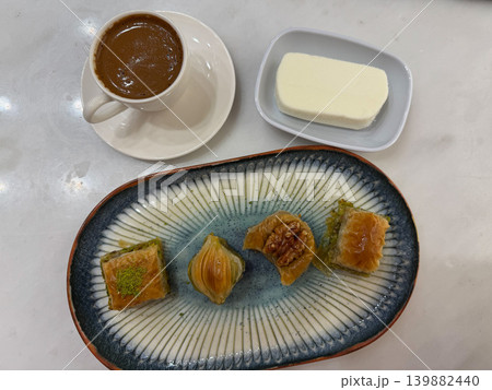 Turkish coffee, assorted baklava pastries served with dondurma ice cream on decorative ceramic plate, marble table in cafe. Cuisine, dessert menu, hospitality branding, food tourism, restaurant 139882440