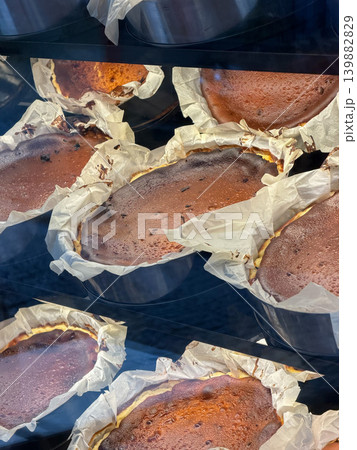 Basque cheesecake pieces bake in parchment-lined molds, glass display in Istanbul bakery, showing caramelized tops, rustic dessert texture. Cafe branding, food tourism, pastry Basque cheesecake pieces bake in parchment-lined molds, glass display in Istanbul bakery, showing caramelized tops, rustic dessert texture. Cafe branding, food tourism, pastry 139882829