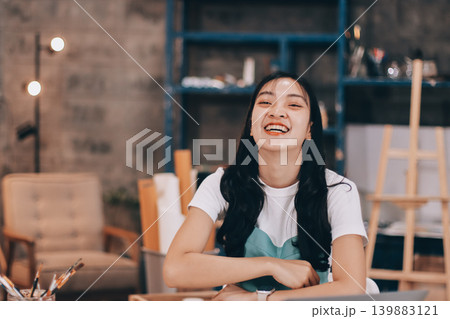 Female artist wears black hat posing near picture indoor the studio 139883121