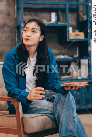 Female artist wears black hat posing near picture indoor the studio Female artist wears black hat posing near picture indoor the studio 139883138