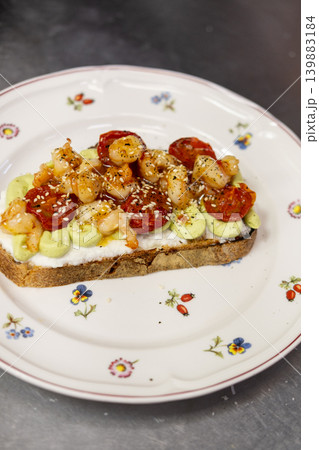 Seafood sandwich. Tasty meal. Portion dish with vegetable prawn sauce served on floral plate on metal table. Dried tomatoes with sesame spice. Seafood sandwich. Tasty meal. Portion dish with vegetable prawn sauce served on floral plate on metal table. Dried tomatoes with sesame spice. 139883184