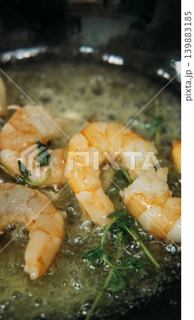 Cooking shrimp. Appetizer recipe. Prawn sizzling in black pan with bubbling butter fresh herbs. Delicious gourmet food preparation. Cooking shrimp. Appetizer recipe. Prawn sizzling in black pan with bubbling butter fresh herbs. Delicious gourmet food preparation. 139883185