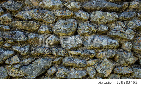 The worn texture of stones in an ancient dry wall. The wall belongs to a Moorish village that has been abandoned for many years in rural Spain. 139883463