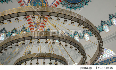 A close look at a chandelier in a mosque reveals detailed metalwork and glass lamps. The design highlights the unique architecture and art found in Islamic buildings. A close look at a chandelier in a mosque reveals detailed metalwork and glass lamps. The design highlights the unique architecture and art found in Islamic buildings. 139883630