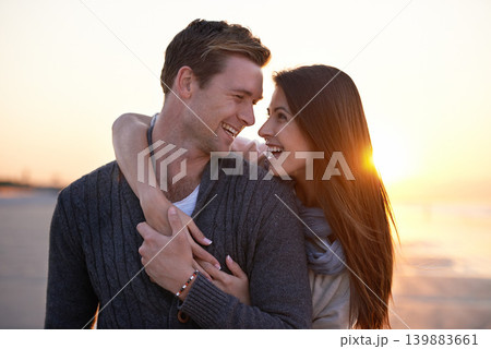 Romance, embrace and happy couple on beach at sunset for tropical holiday adventure, love and bonding together. Smile, man and woman on date with ocean, evening sky and hug on vacation in nature. 139883661