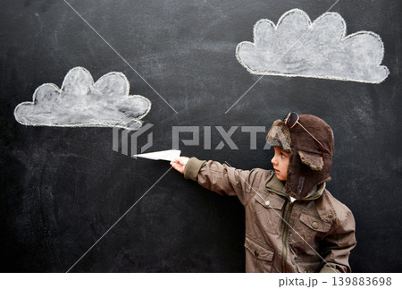 Children, chalkboard and paper plane with boy in studio on black background for fantasy game. Education, class and kid pilot in costume at playing school for growth, learning or child development 139883698
