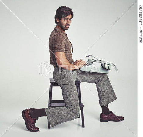 Man, vintage and pipe with typewriter in studio on grey background, confident and typing in chair. Fashion, retro and smart style in old school with elegance on fashionable and fancy clothes. Man, vintage and pipe with typewriter in studio on grey background, confident and typing in chair. Fashion, retro and smart style in old school with elegance on fashionable and fancy clothes. 139883767