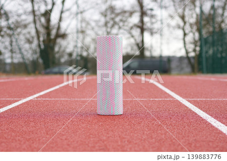 Foam roller on running track outdoor recovery fitness training concept Foam roller on running track outdoor recovery fitness training concept 139883776