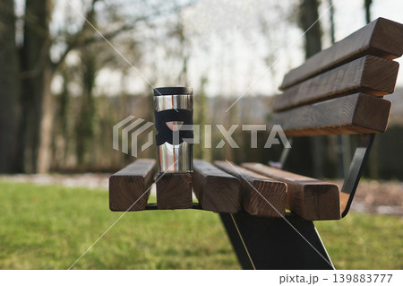 Thermos cup on wooden bench in park calm morning scene 139883777