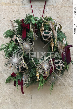 Luxury festive wreath with metallic ornaments hanging on stone exterior wall Luxury festive wreath with metallic ornaments hanging on stone exterior wall 139883805