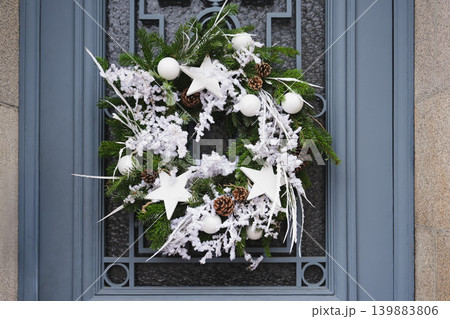 Christmas wreath with branches and white balls on a glass door Christmas wreath with branches and white balls on a glass door 139883806