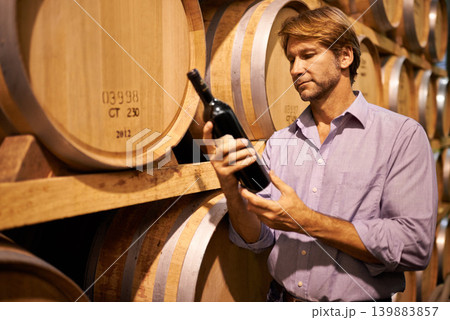 Barrels, cellar and man with bottle of wine for reading label in winery, warehouse or distillery. Agriculture, industry and mature male person by wooden containers with alcohol beverage in storage. Barrels, cellar and man with bottle of wine for reading label in winery, warehouse or distillery. Agriculture, industry and mature male person by wooden containers with alcohol beverage in storage. 139883857