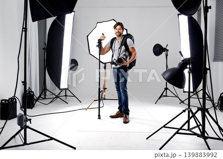 Photographer, portrait and lighting with equipment in studio for career, behind the scenes or electronics. Photography, person or happy with cameras, flash and shooting gear for photoshoot or passion 139883992