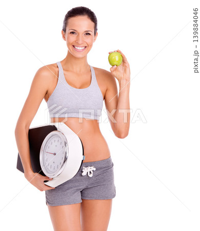 Fitness, apple and portrait of woman with scale in studio for weight loss, health and wellness diet. Vitamins, nutrition and female person eating organic fruit and measure by white background. Fitness, apple and portrait of woman with scale in studio for weight loss, health and wellness diet. Vitamins, nutrition and female person eating organic fruit and measure by white background. 139884046