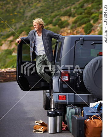 Man, car and looking out door on road trip for travel, break or stop in nature or sightseeing. Young or handsome male person, tourist or traveler exploring or enjoying view or holiday from vehicle 139884235