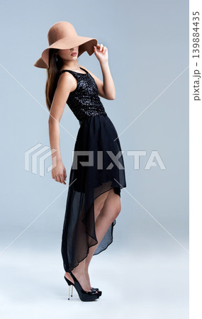 Confidence, fashion and woman in hat with glamour, cocktail dress and vintage aesthetic in studio. Classic, chic and elegant style with girl on grey background for luxury, grace and classy model. Confidence, fashion and woman in hat with glamour, cocktail dress and vintage aesthetic in studio. Classic, chic and elegant style with girl on grey background for luxury, grace and classy model. 139884435