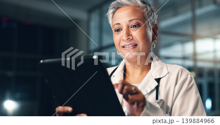 Doctor, mature woman and happy with tablet in night, typing or smile for results, meme or notification in hospital. Senior nurse, digital touchscreen or funny video with click, scroll or social media 139884966