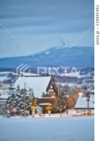 雪化粧した雄大な山並みと雪に包まれた北国の街並み、伝統的な屋根の風景 雪化粧した雄大な山並みと雪に包まれた北国の街並み、伝統的な屋根の風景 139885461