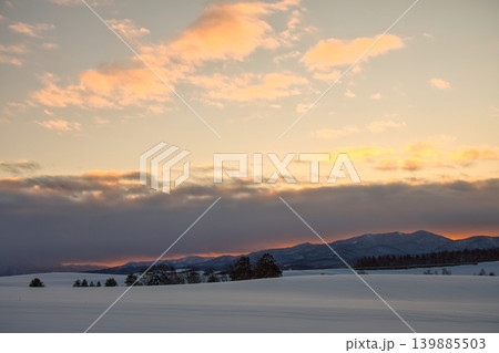 夕焼けの美しい雲とグラデーション空に映える冬の雪山と広大な雪原 139885503