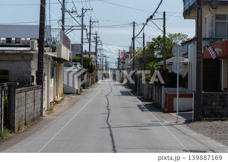 電柱が立ち並び電線の影が道の真ん中にある車も人も通っていない長い直線の通り 139887169