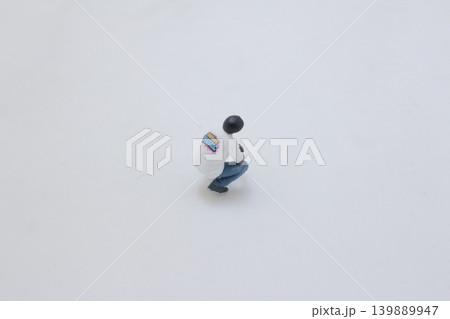 Miniature figure crouching isolated on white background Miniature figure crouching isolated on white background 139889947