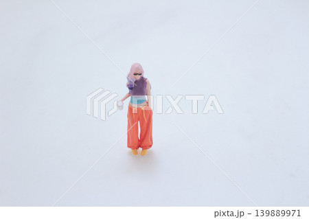 Miniature pedestrian holding drink wearing colorful outfit Miniature pedestrian holding drink wearing colorful outfit 139889971