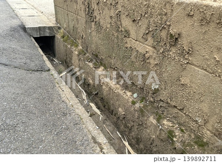 老朽化が進む路肩のコンクリート擁壁と隣接する側溝 老朽化が進む路肩のコンクリート擁壁と隣接する側溝 139892711