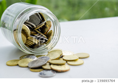 Gold coins pouring from a tilted jar in a minimal finance scene Gold coins pouring from a tilted jar in a minimal finance scene 139893764