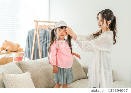 自宅のリビングで娘の着替えを手伝う母親 139894067
