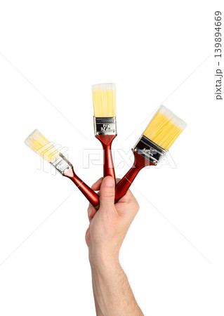 three brushes in a raised hand isolated on a white background three brushes in a raised hand isolated on a white background 139894669